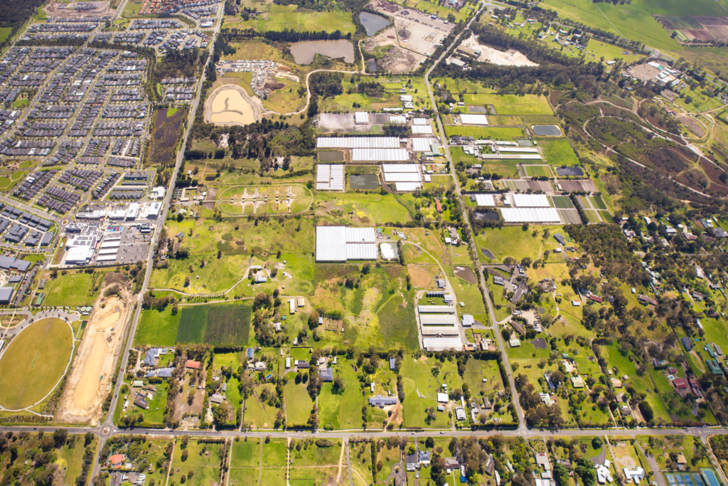 Aerial view looking north along Craig Road, Devon Meadows, showing the Devon Meadows Estate land beside Junction Village, local shops, the swimming centre and sports ovals