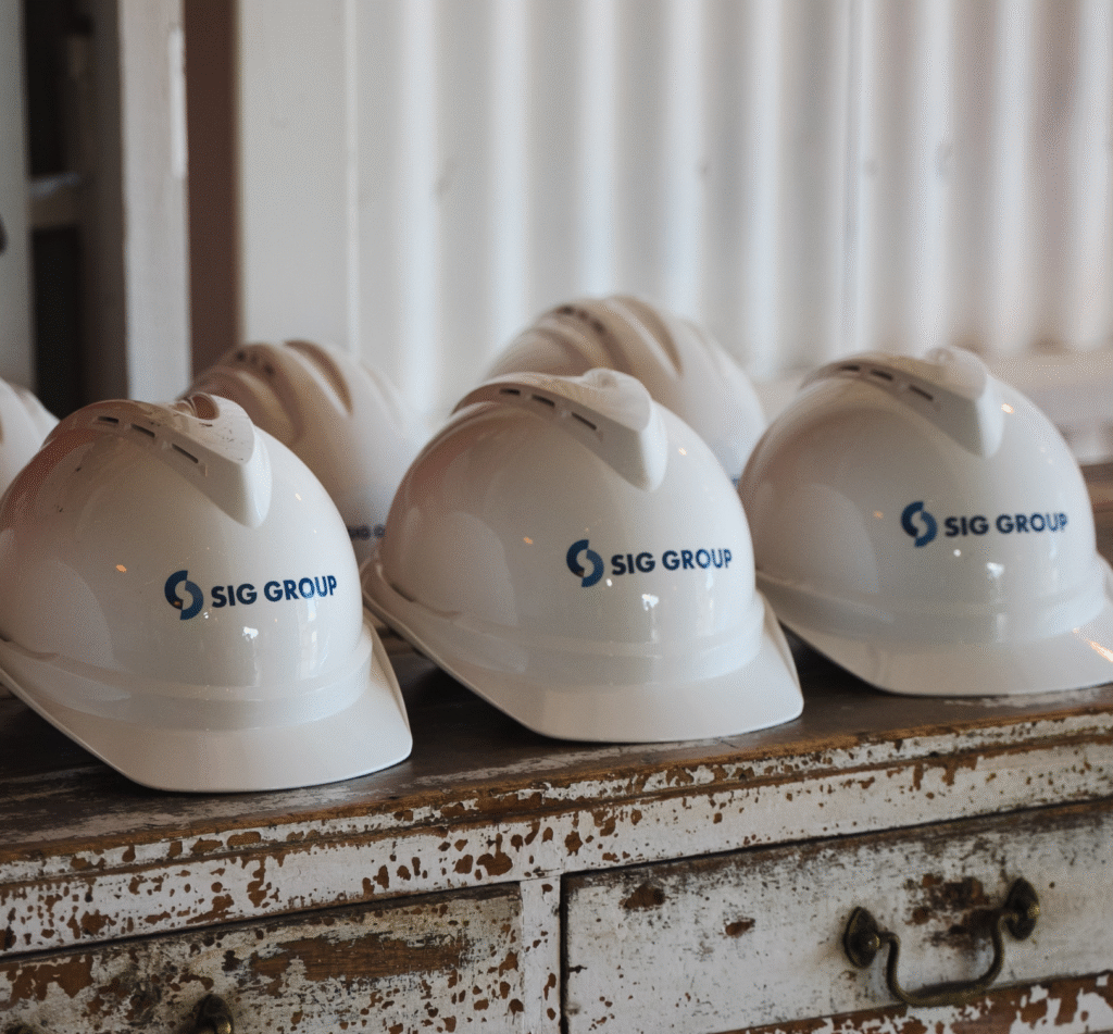 Masterplanned residential community developed by SIG Group, aerial view of a completed land community in Australia, streetscape within a masterplanned neighbourhood, SIG Group team collaborating on a property development project, leadership team reviewing plans and strategy, residential land development under construction, infrastructure works within a community, civil construction on a land subdivision, families enjoying open space, park and playground within a neighbourhood, community streetscape designed for everyday living, masterplan layout for a residential project, site plan showing staged development, planning documentation for a community, SIG Group sales office interior, property sales office for a land development, customer consultation space within a sales office